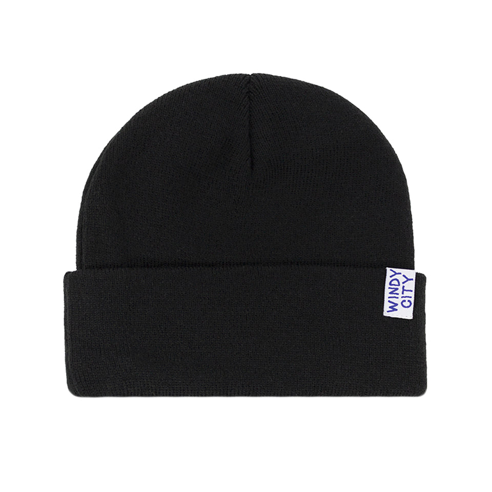 Rear view of black, acrylic knit beanie: wide rollover cuff with small white tag with Windy City embroidered in navy capitals