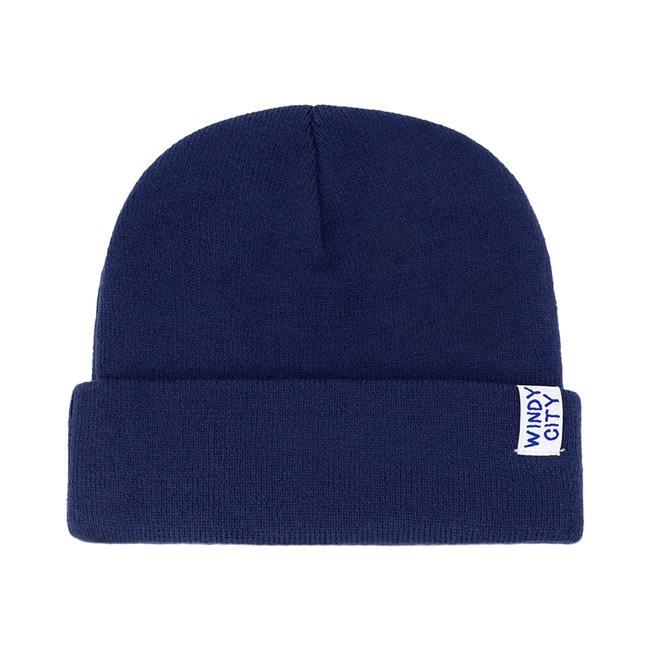 Rear view of navy blue, acrylic knit beanie: wide rollover cuff, small white tag with Windy City embroidered in navy capitals