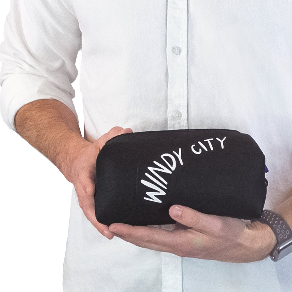 Closeup of male model's hands holding black silicone pouch, showing long side with wave texture & white Windy City text