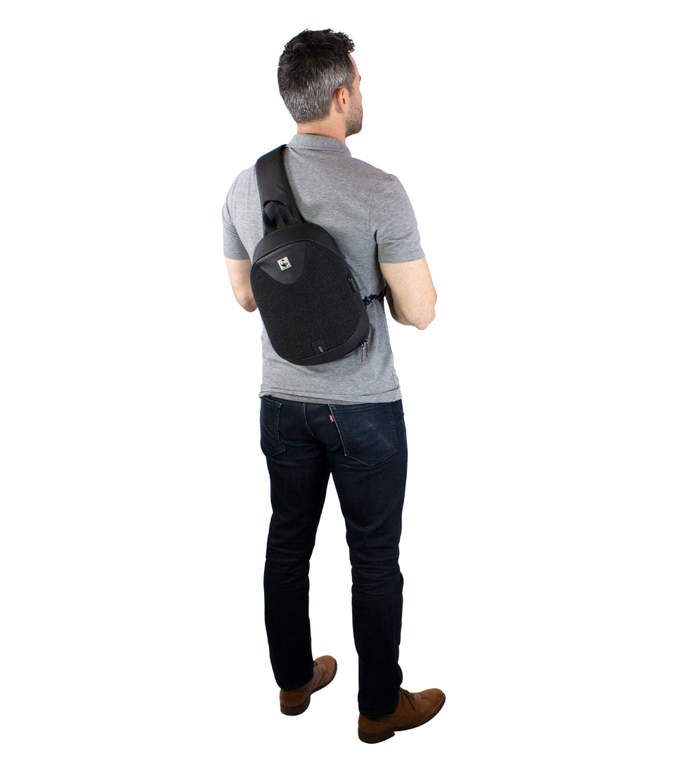 Rear view of male model, wearing black poly-fabric sling bag strapped across his back